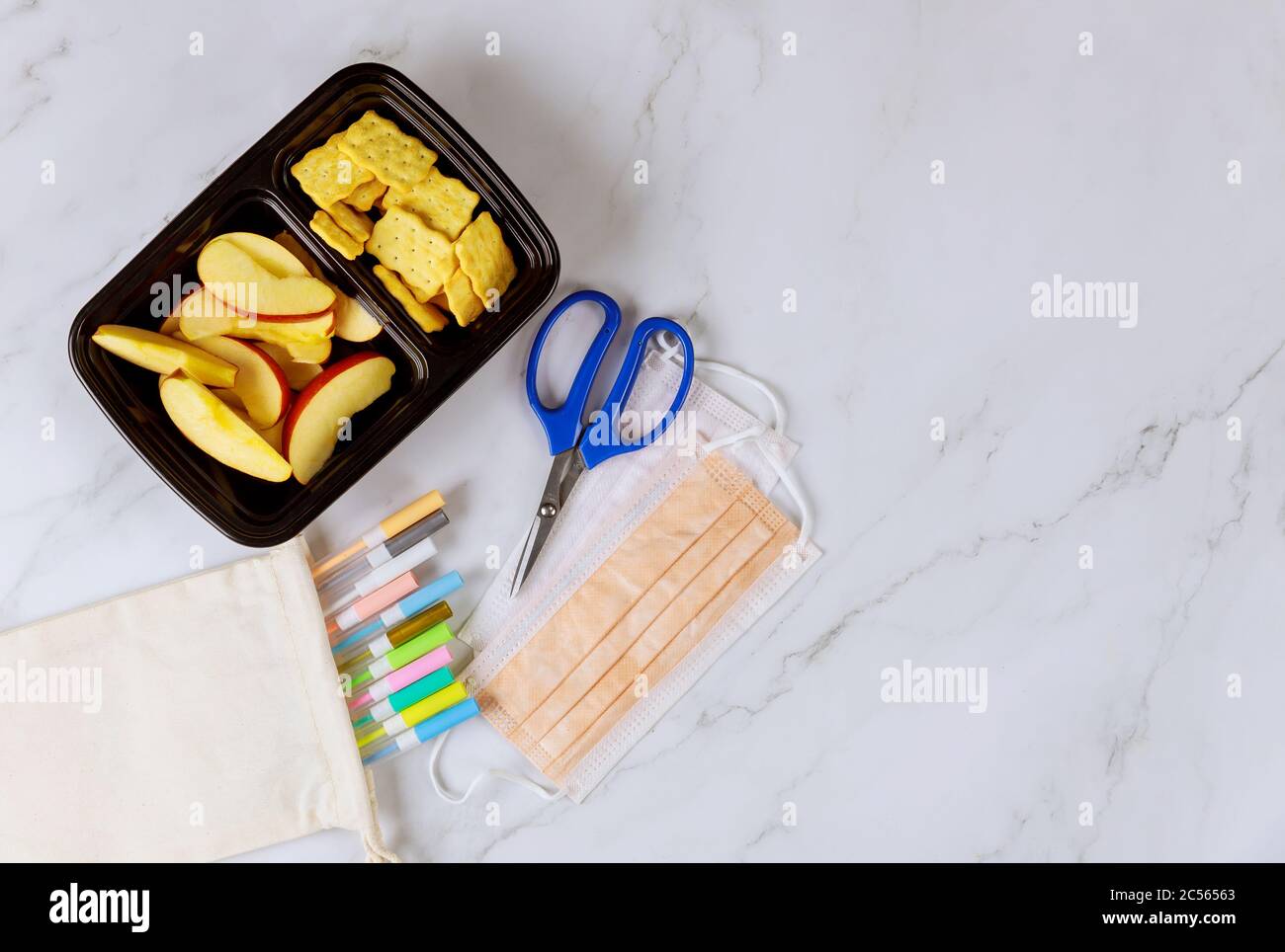 Pranzo al sacco con mele a fette, cracker e forniture scolastiche. Vista dall'alto. Foto Stock