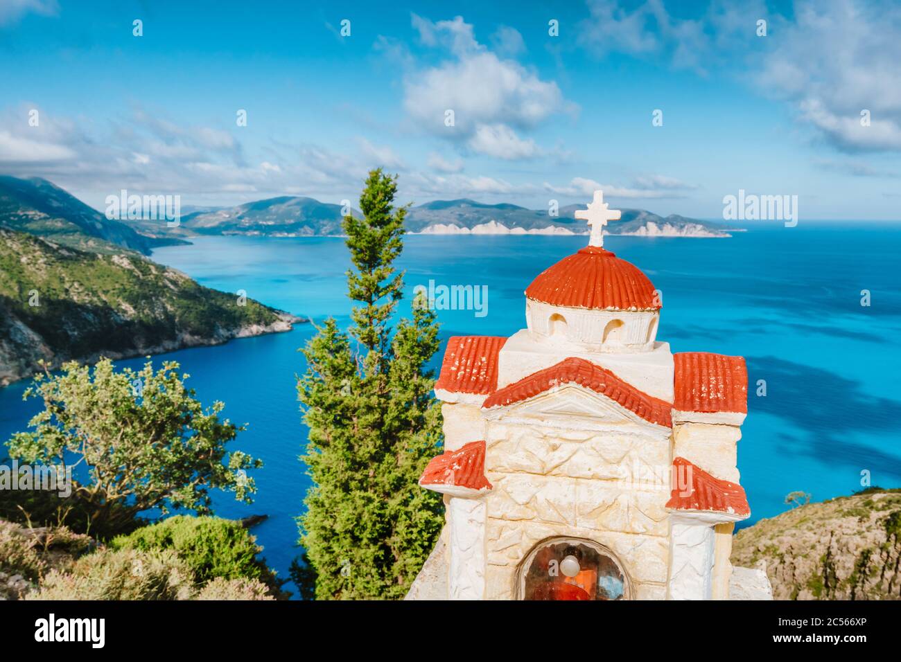 Vacanze estive in Grecia. Santuario Proskinitari di colore arancione con mare blu e nuvole bianche sullo sfondo. Foto Stock