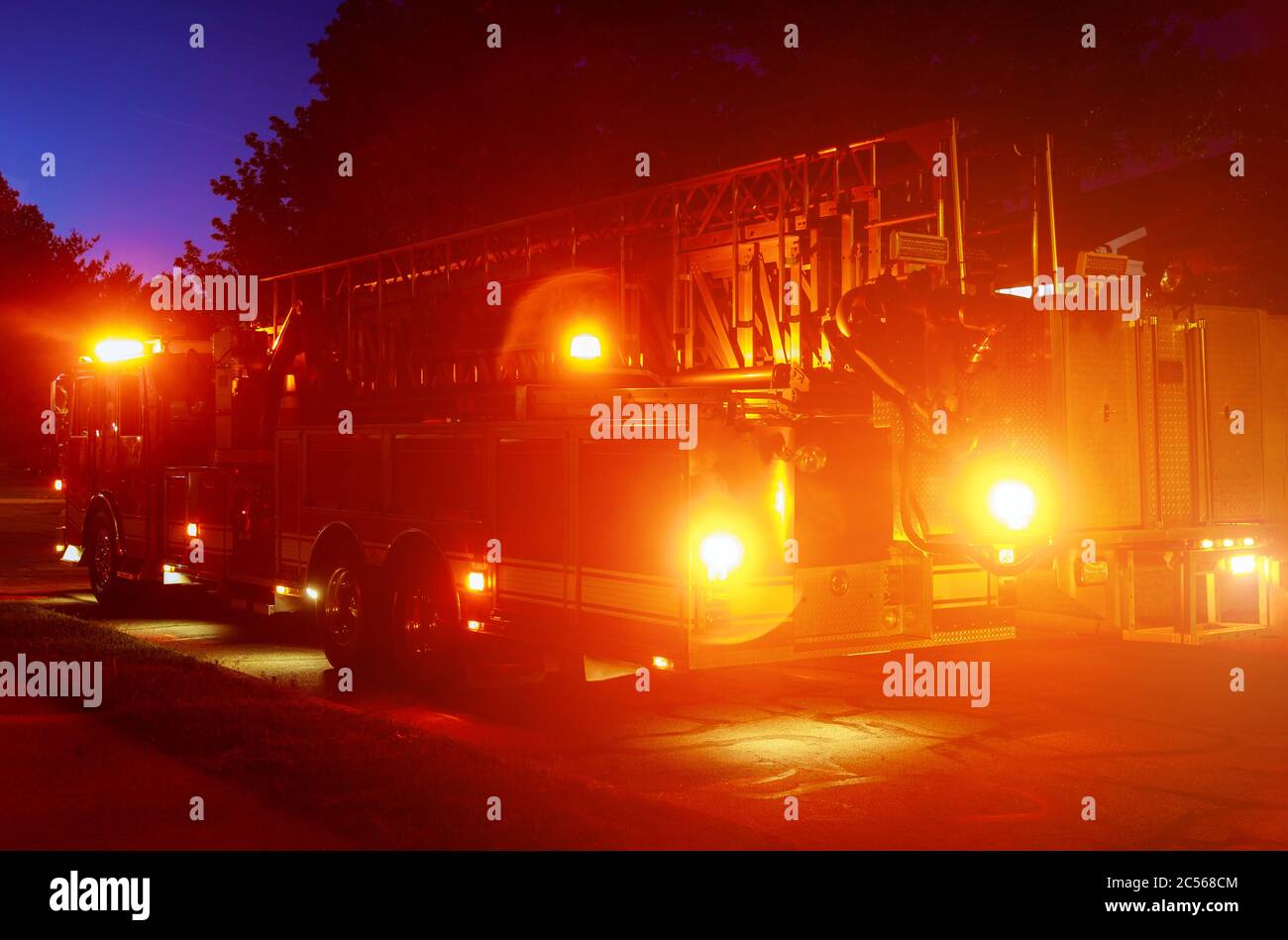Camion antincendio con spie di emergenza lampeggianti una scena di risposta su una strada di notte Foto Stock