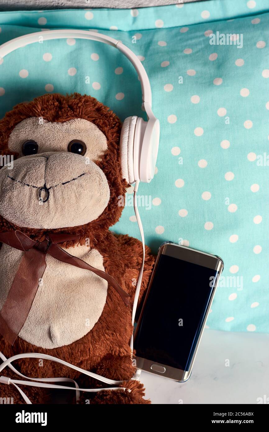 Soffice giocattolo a scimmia con cuffie e uno smartphone su uno coperta  verde Foto stock - Alamy
