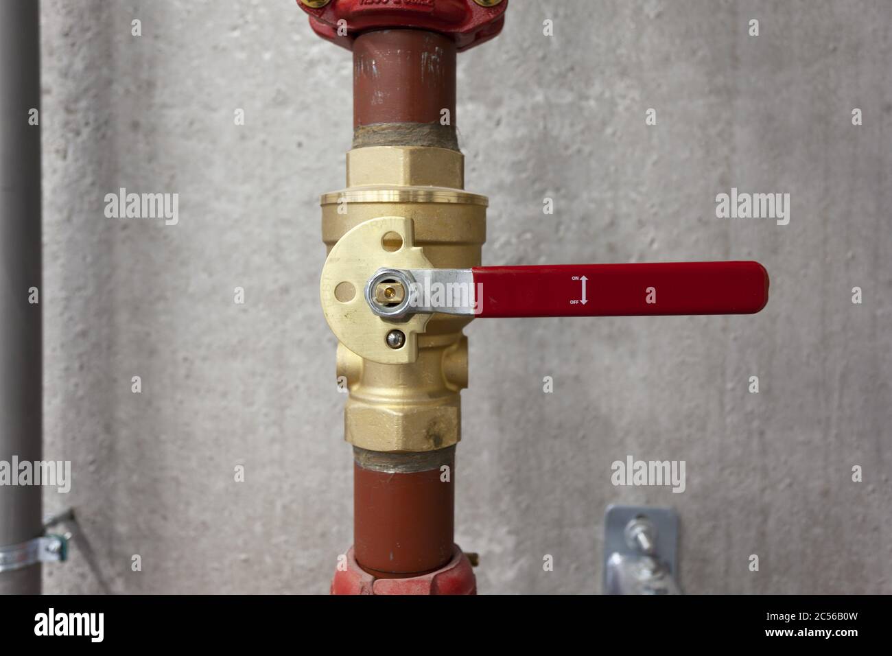 Colpo di primo piano di un tubo rosso con una valvola su sfondo grigio della parete Foto Stock