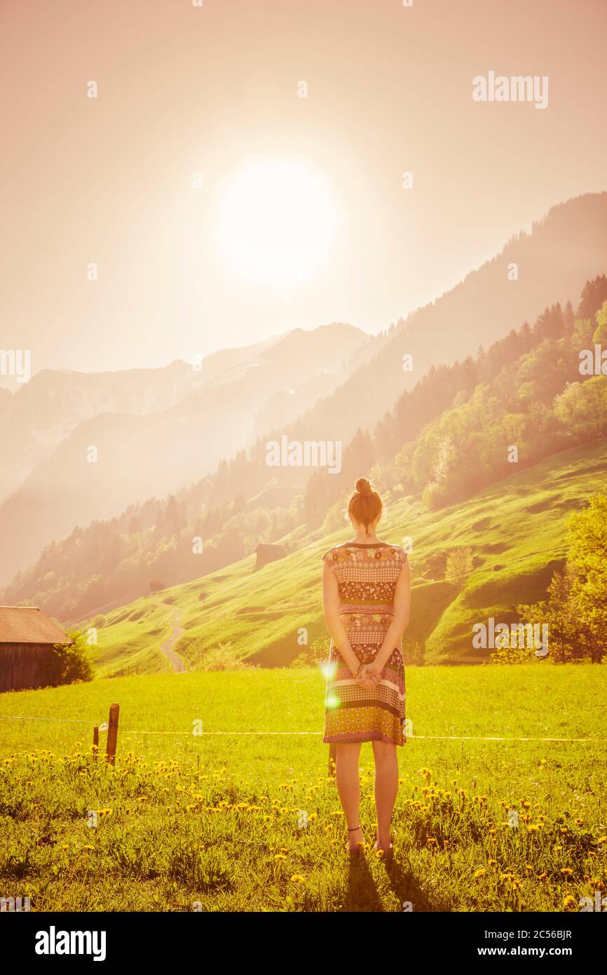 Donna con abito colorato in paesaggio montano svizzero Foto Stock