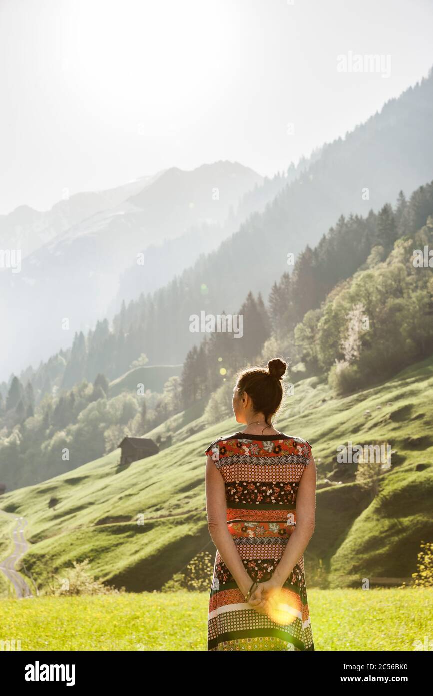 Donna con abito colorato in paesaggio montano svizzero Foto Stock
