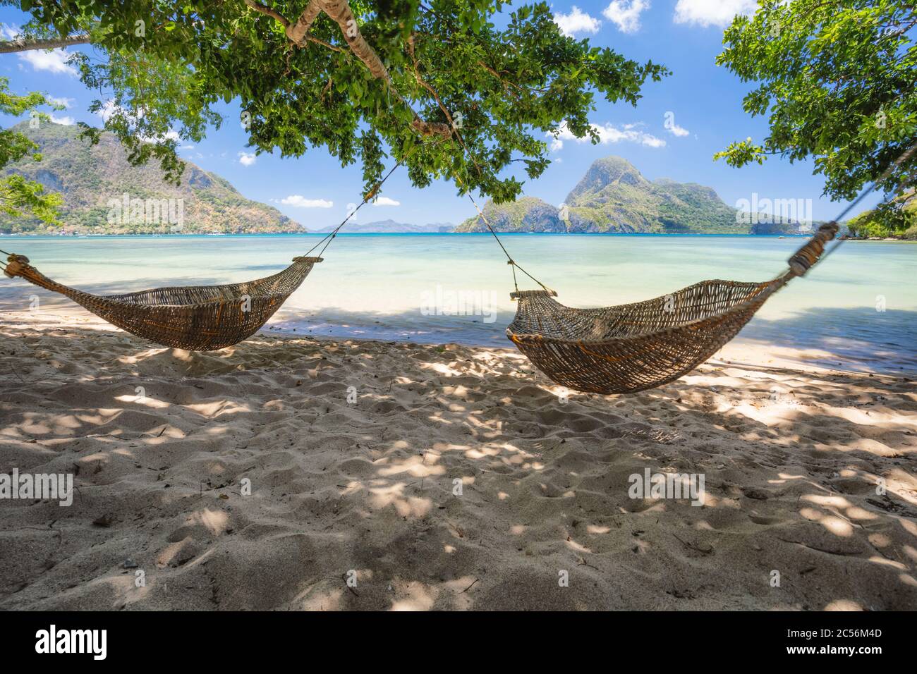 El Nido, Palawan, Filippine. Amache di bambù sulla riva all'ombra. Splendida laguna tropicale con l'epica isola Cadlao sullo sfondo. Foto Stock