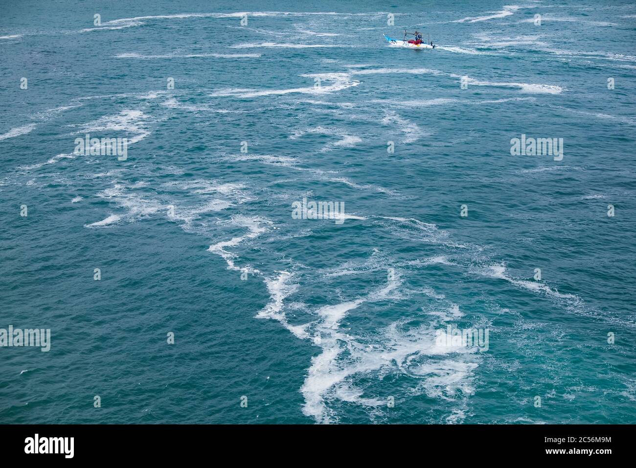 Una piccola barca da pesca naviga in mare mosso con onde al largo della costa dello Sri Lanka Foto Stock