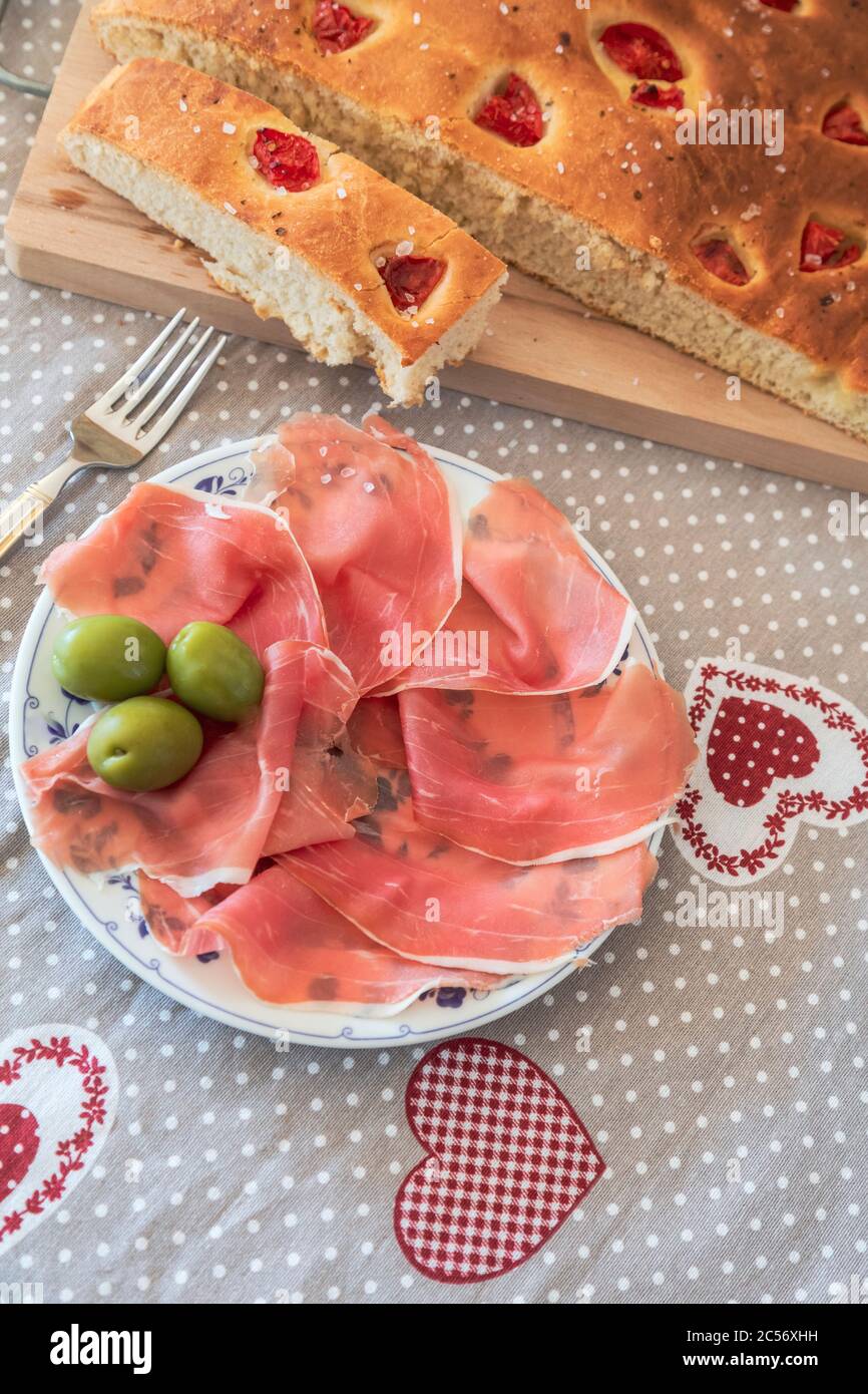 Focaccia pugliese fatta in casa, servita con prosciutto e olive di Parma, piatti tipici italiani Foto Stock