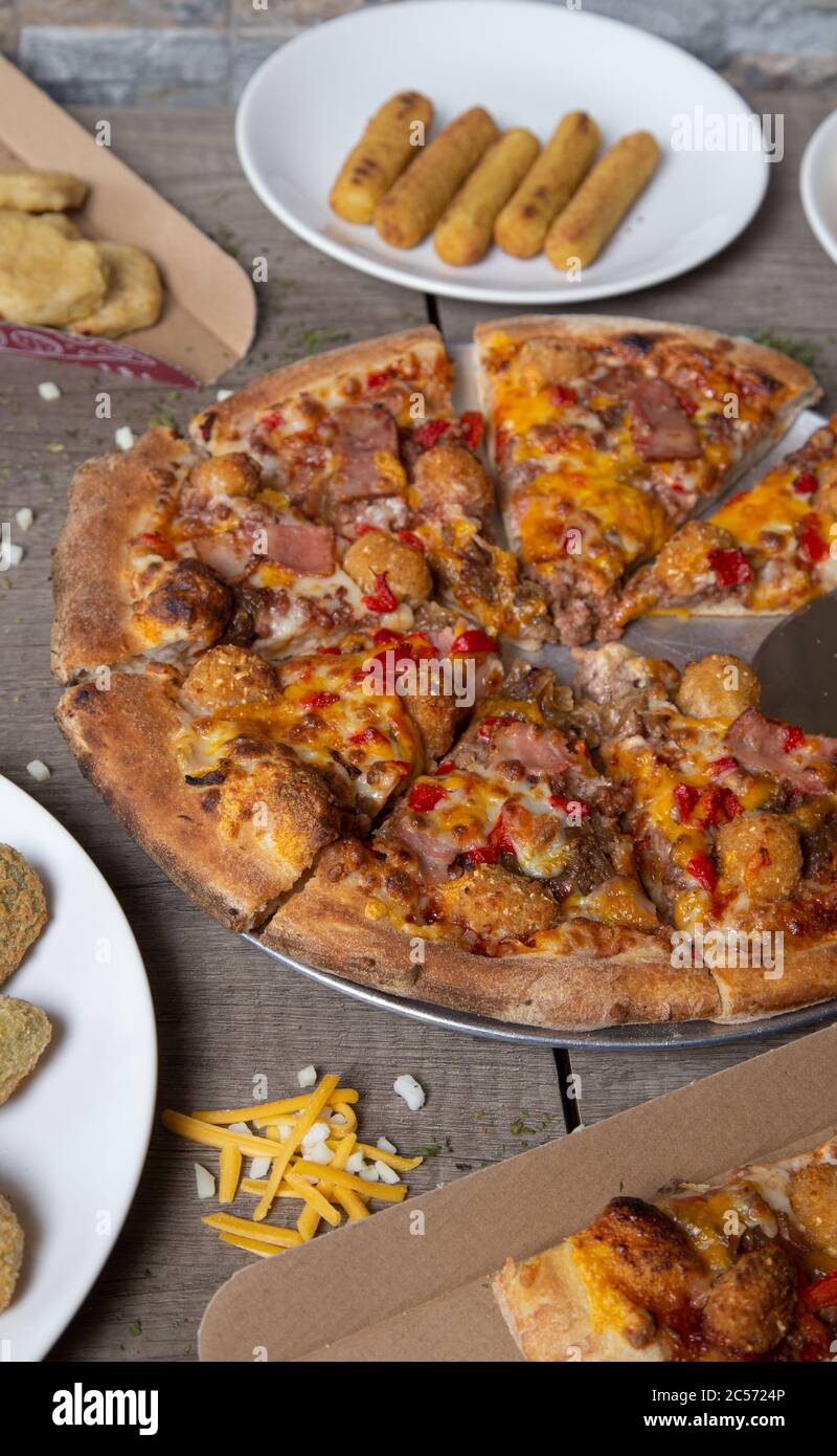 assortimento di accessori e pizza al barbecue tagliata sul tavolo del  ristorante. Pizzeria, bocconcini, bastoncini di pollo Foto stock - Alamy