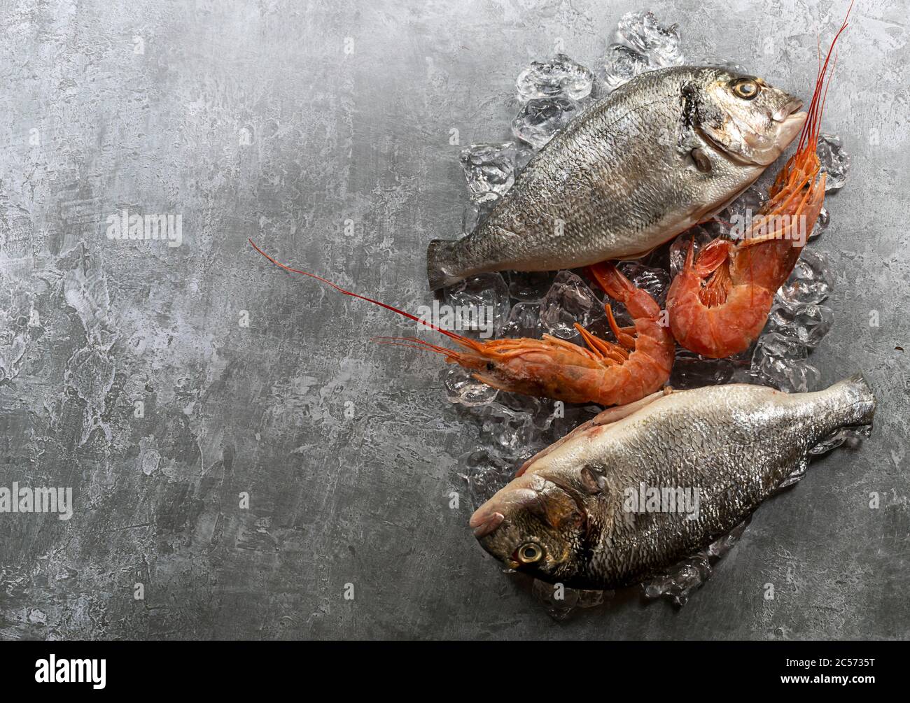 Pesce fresco e gamberi dorado crudi sui cubetti di ghiaccio. Foto Stock
