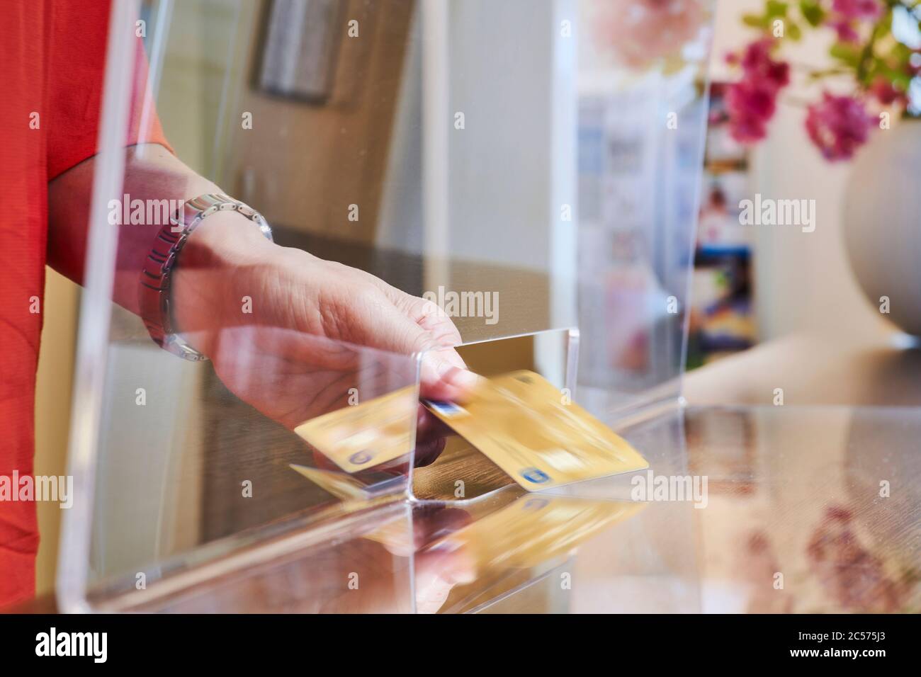Protezione simbolica da infezioni delle immagini, disco trasparente di protezione sputa, donna passa la sua carta attraverso lo slot passante Foto Stock