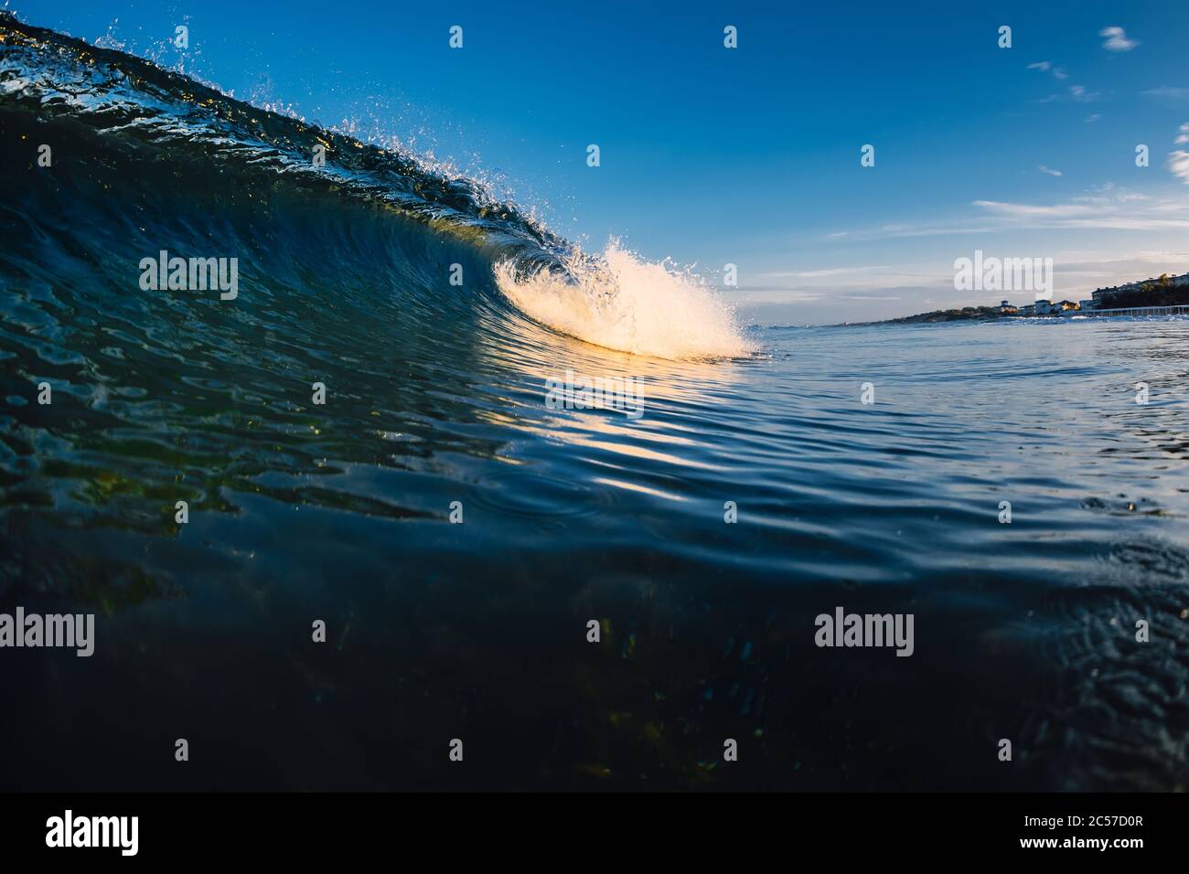 Barile che infrangono l'onda in oceano con toni caldi e spiaggia Foto Stock