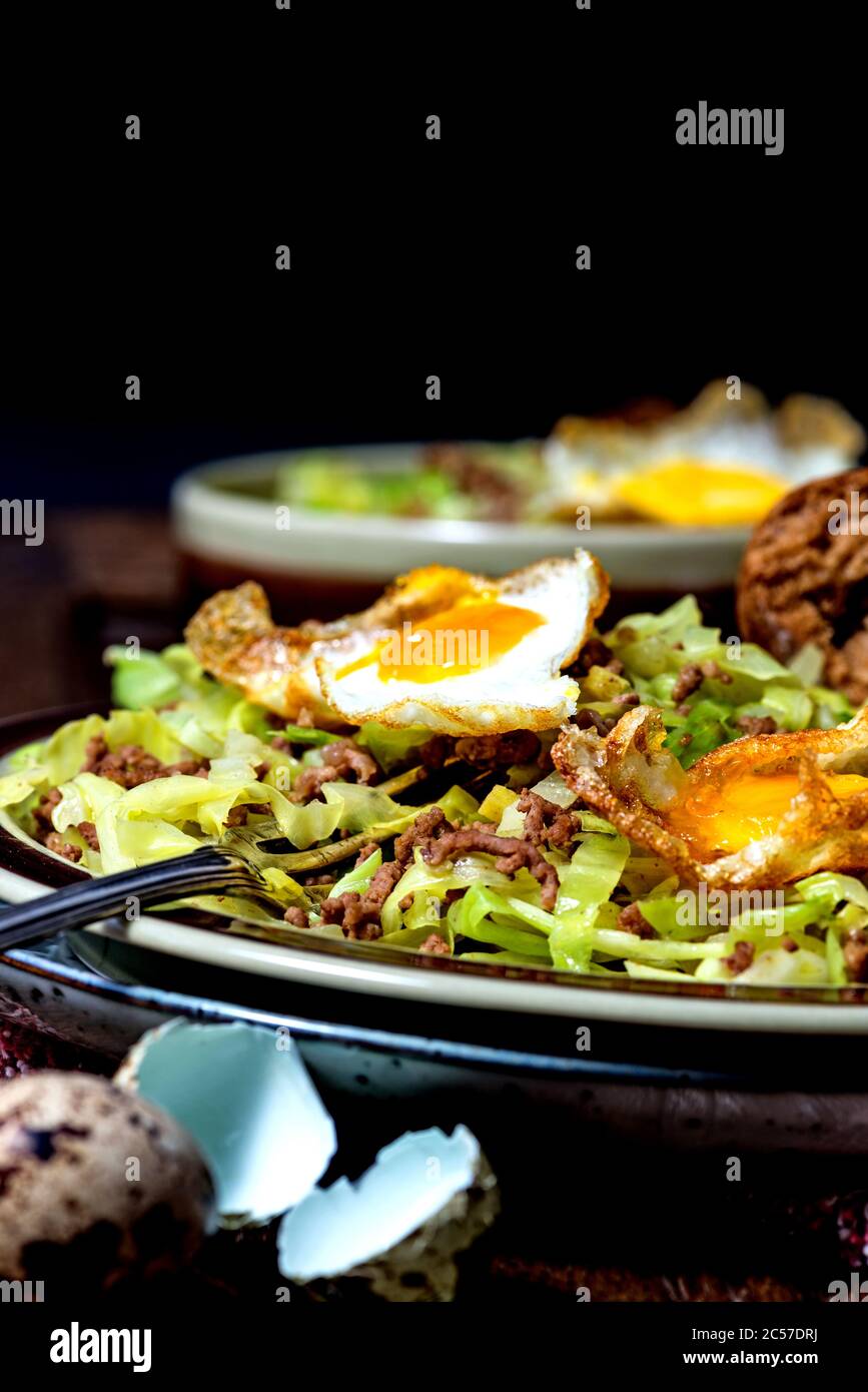 Piatto in padella, cavolo appuntito, manzo tritato, uova fritte da uova di quaglia Foto Stock