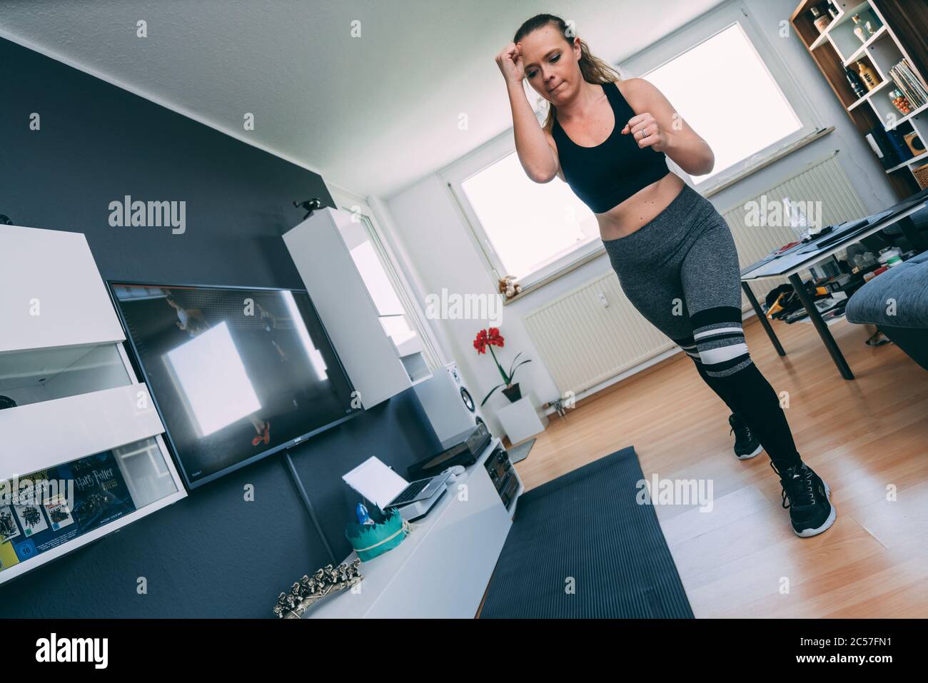 Europa, Germania, Rosenheim, giovane donna sta facendo allenamento sportivo a casa, Livingroom Foto Stock