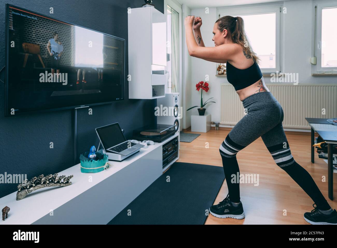 Europa, Germania, Rosenheim, giovane donna sta facendo allenamento sportivo a casa, Livingroom Foto Stock