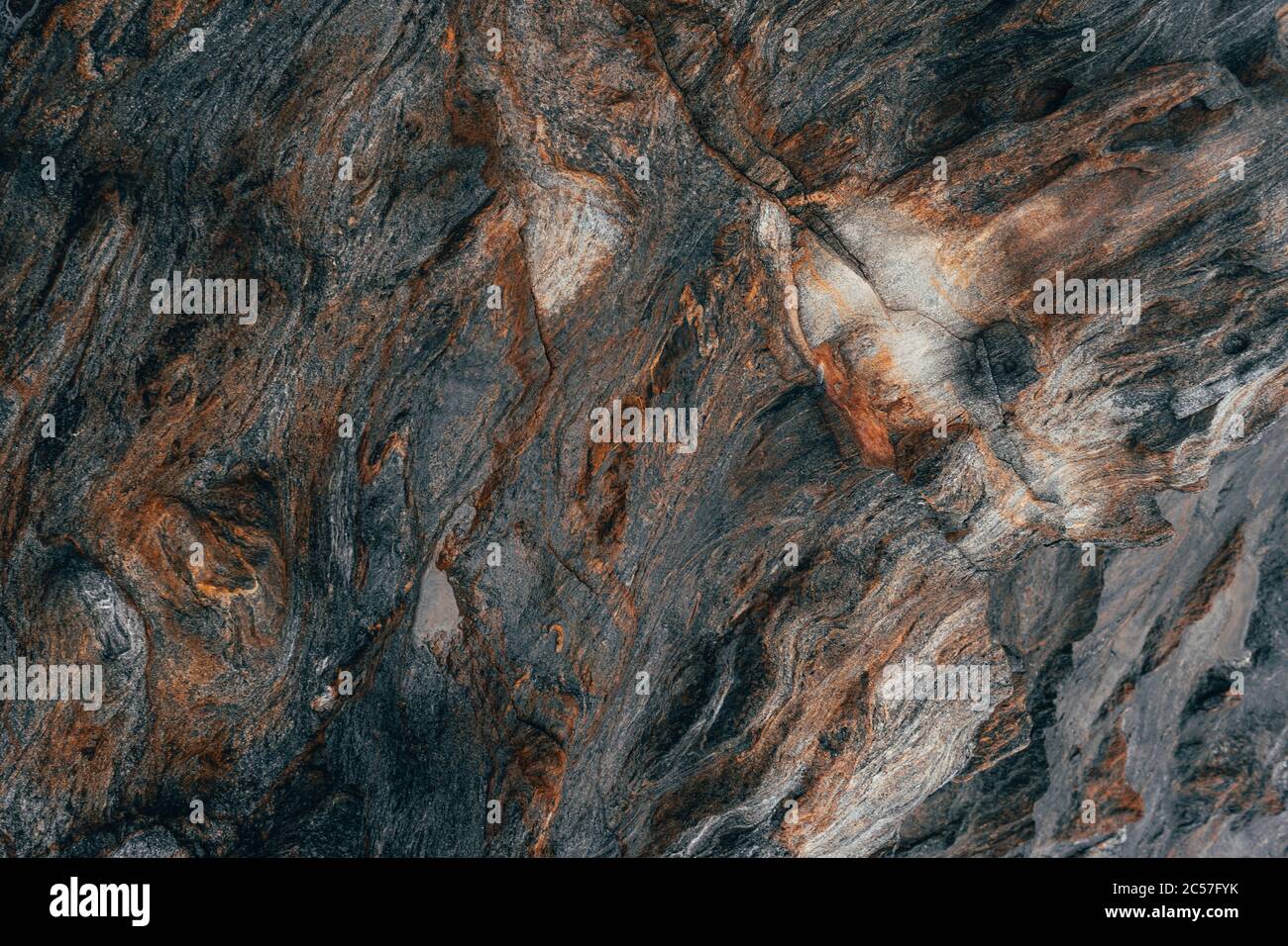 Primo piano di una superficie rocciosa di colore marrone rossastro, nero e bianco Foto Stock