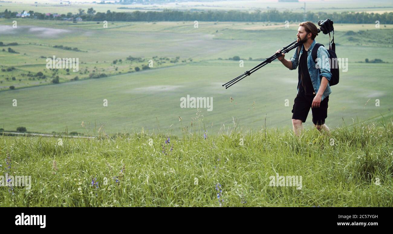 Uomo che porta il treppiede con la fotocamera Foto Stock