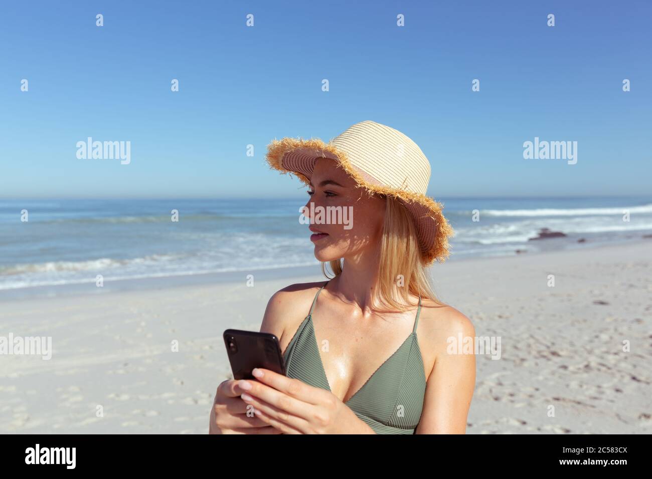 Donna che utilizza smartphone sulla spiaggia Foto Stock