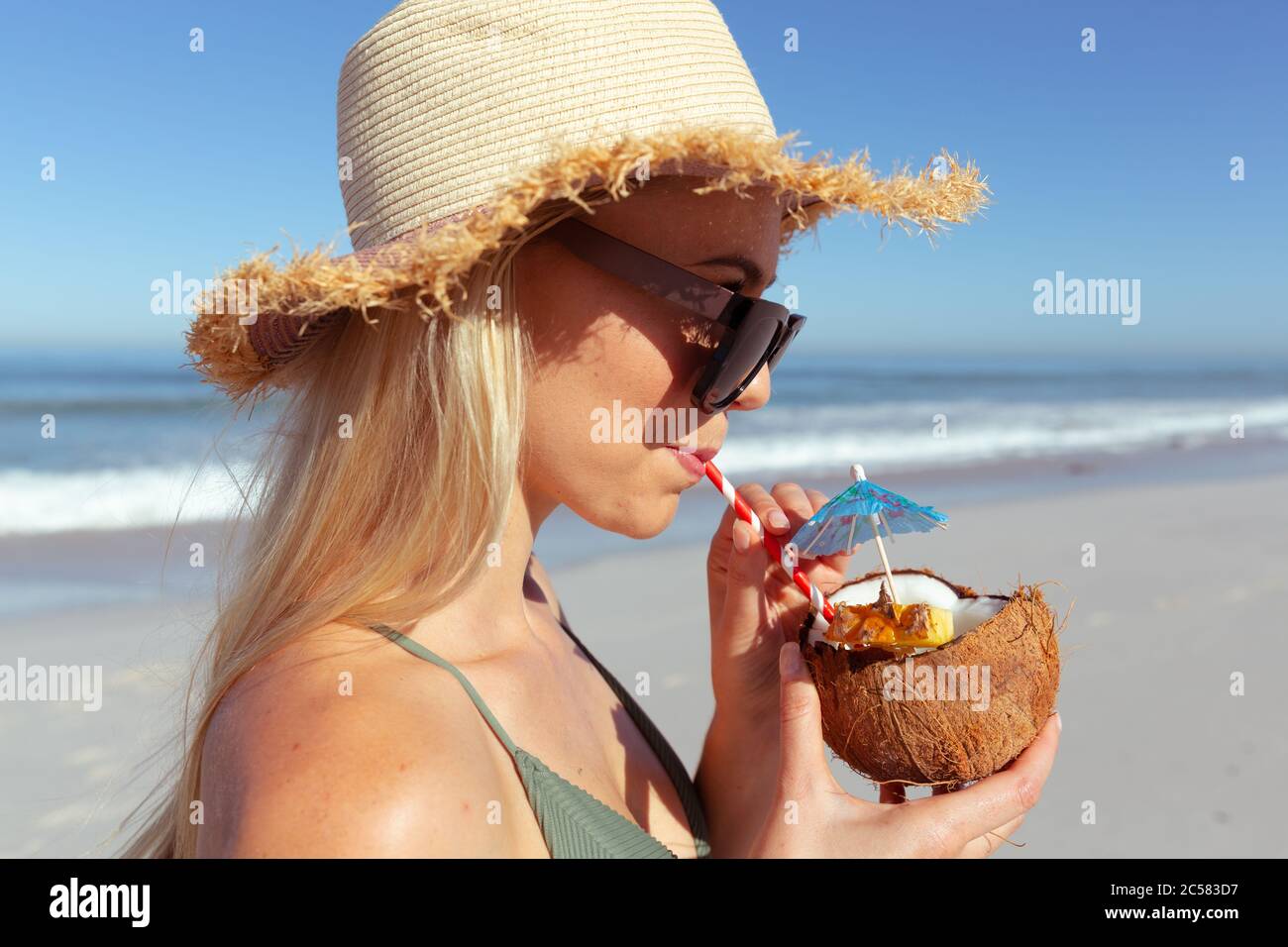 Donna che beve cocktail di cocco sulla spiaggia Foto Stock