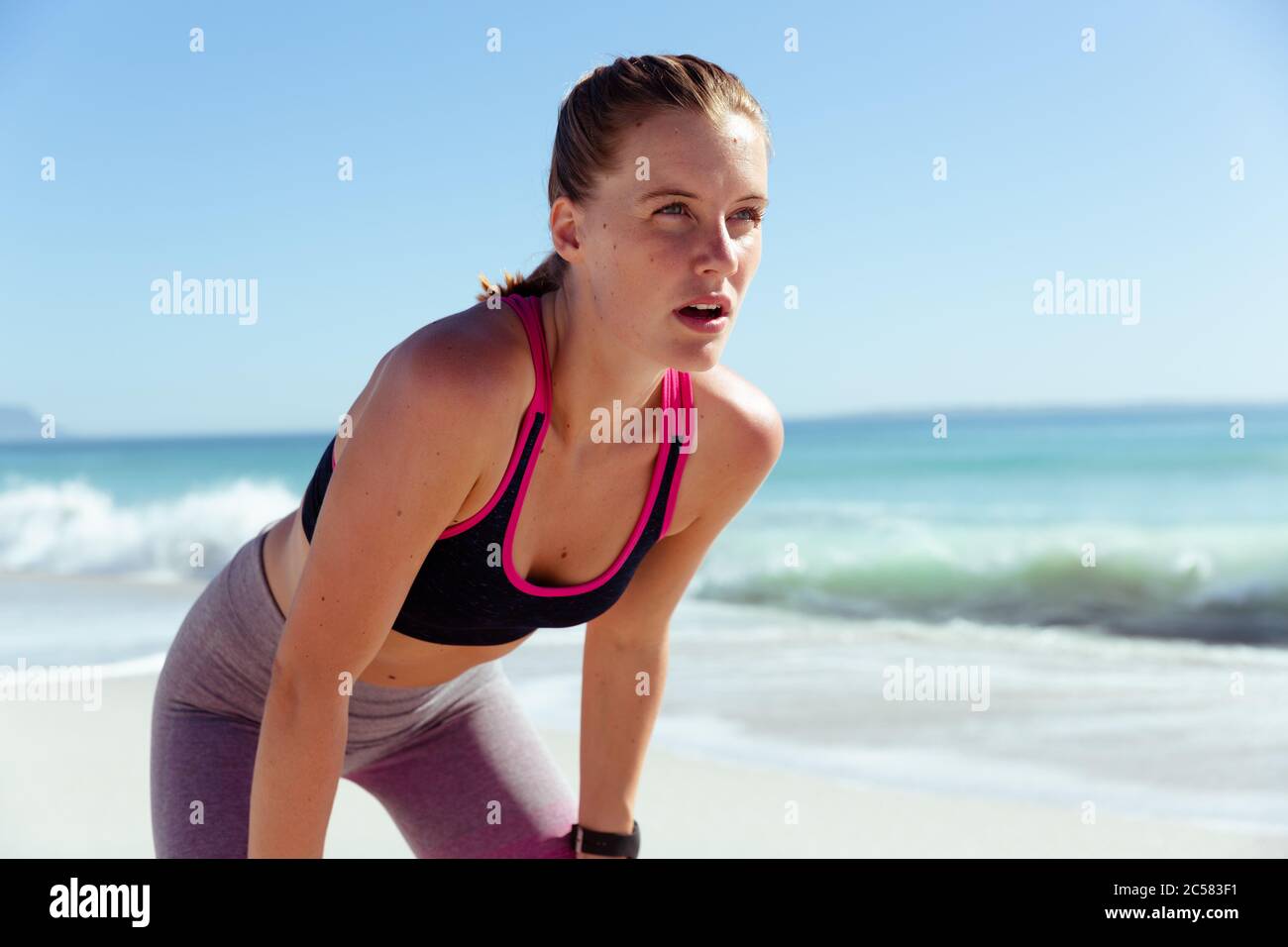 Donna che prende una pausa mentre corre sulla spiaggia Foto Stock