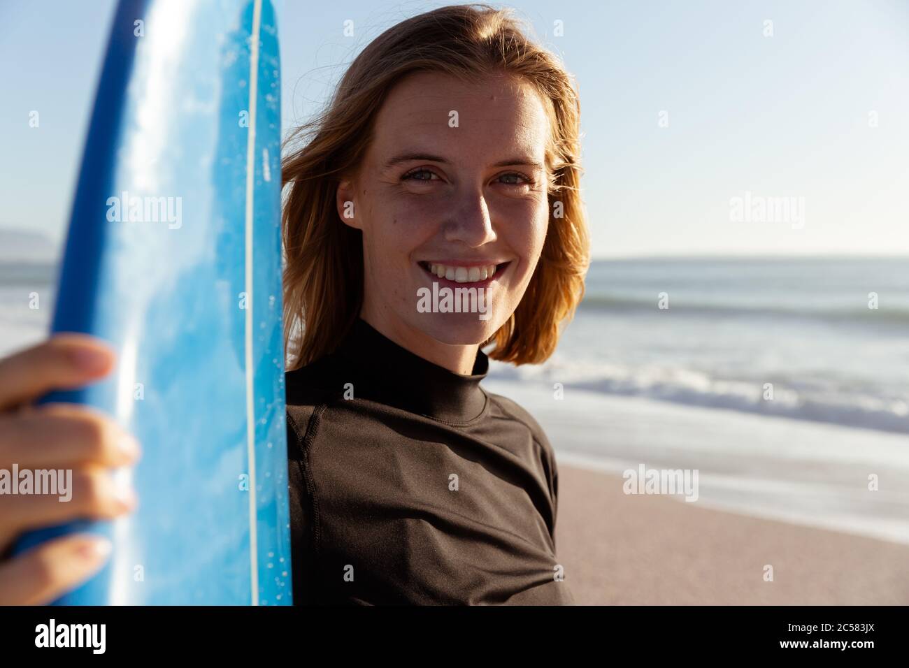 Ritratto di donna sorridente con tavola da surf in spiaggia Foto Stock