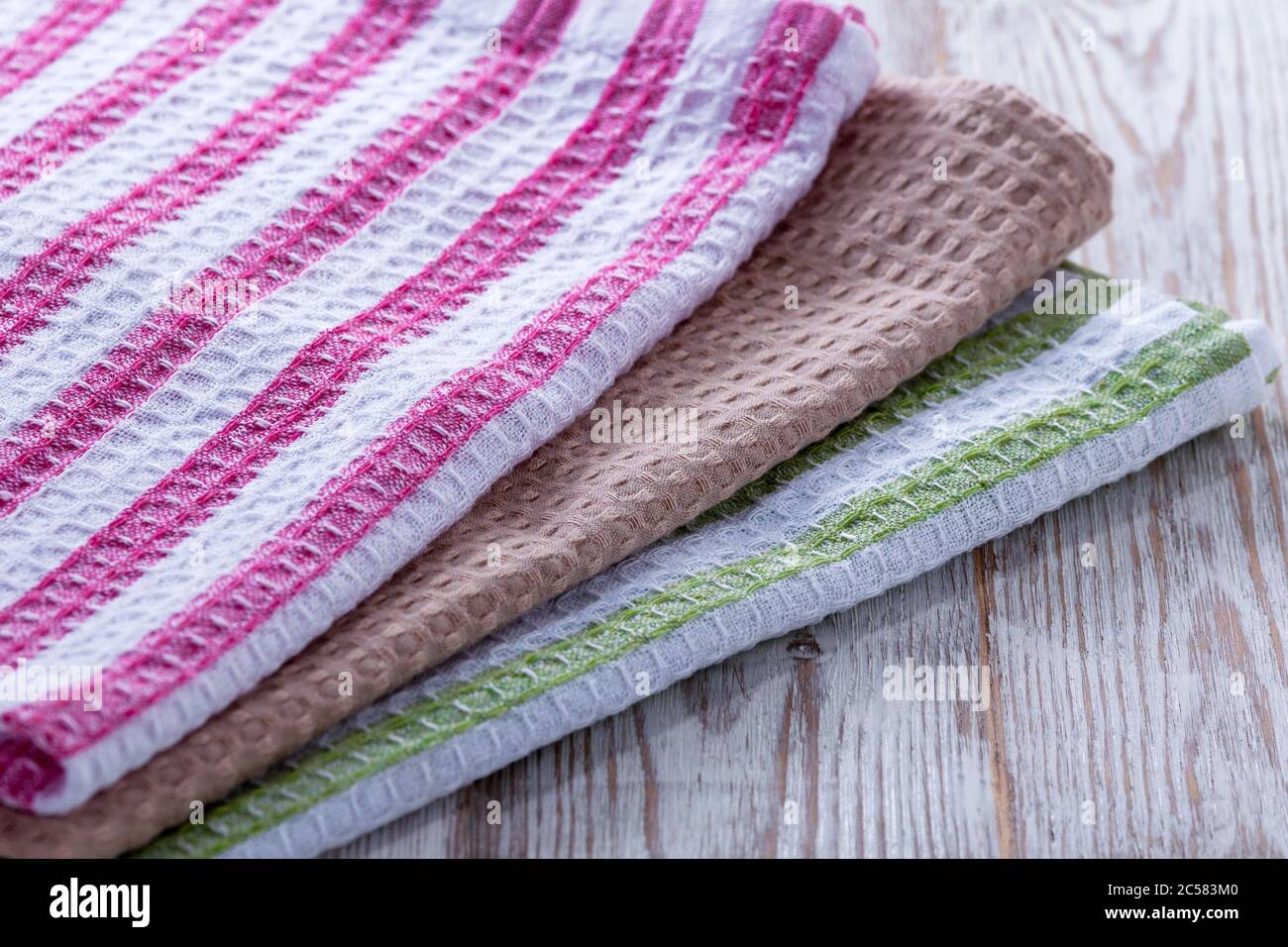 Una pila di asciugamani e tovaglioli che si trovano sul tavolo. Pulire gli asciugamani da cucina e le salviette per le mani che si trovano sul tavolo. Ordine in cucina. Tovaglioli colorati, asciugamani. Foto Stock