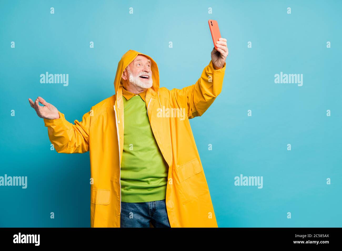 Ritratto del suo bel allegro allegro funky felice uomo grigio-capelli con topcoat giallo prendendo facendo selfie divertirsi isolato su brillante vivido Foto Stock