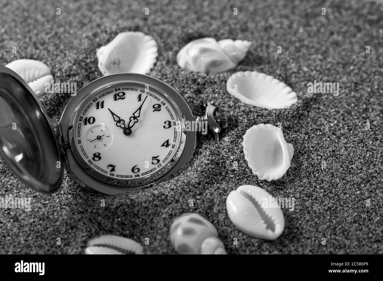 Un vecchio orologio da tasca sdraiato nella sabbia circondato da conchiglie. L'orologio cadde nella sabbia. Il tempo è in esecuzione. Tempo di esecuzione. Tempo di perdita. Foto Stock