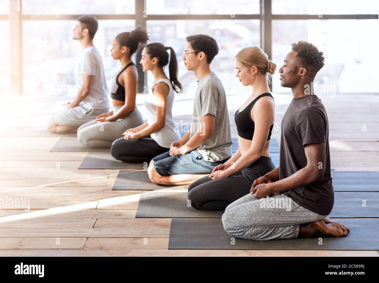 Concetto di benessere. Giovani sportivi in classe yoga facendo insieme esercizi di meditazione Foto Stock