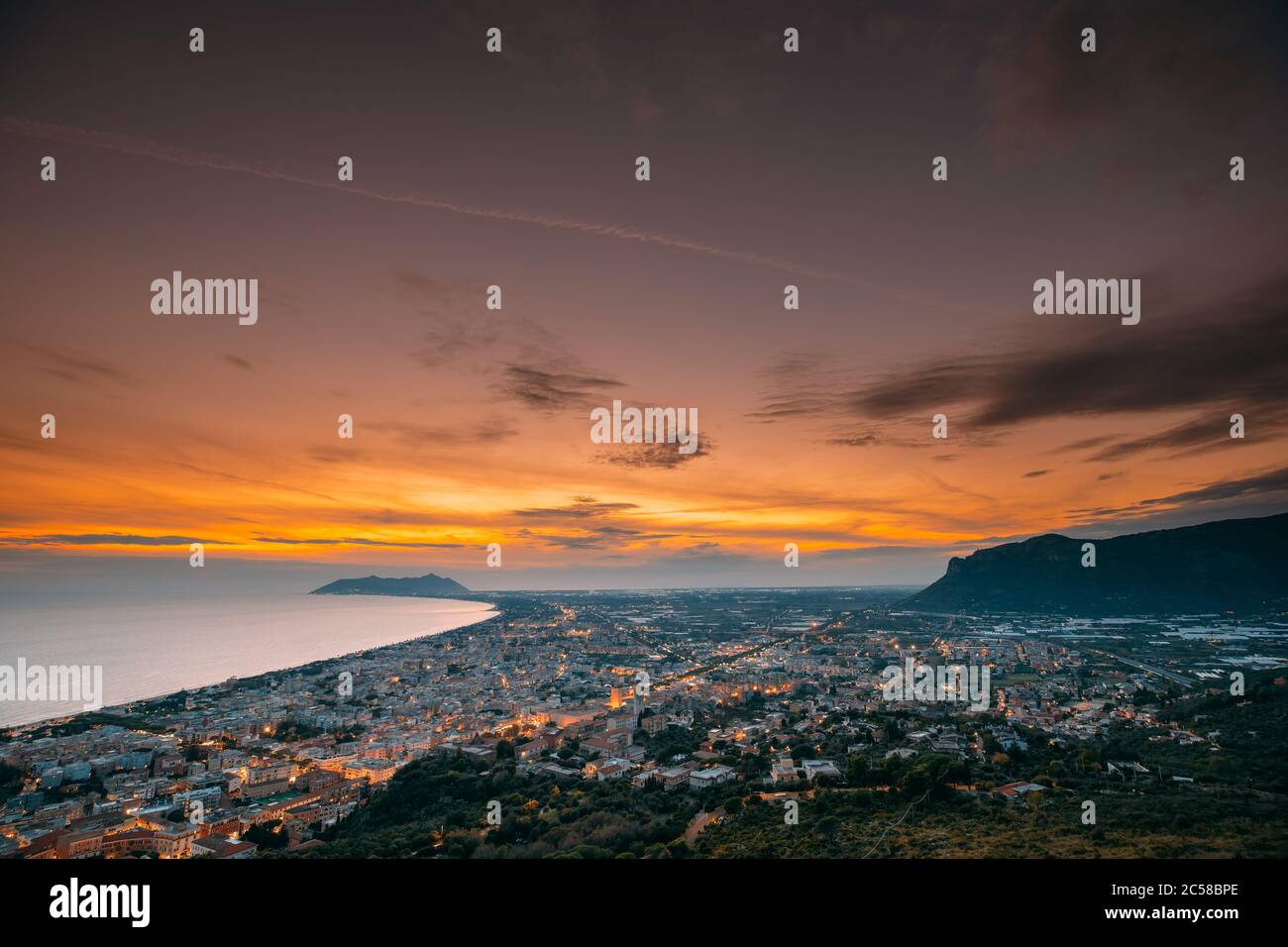 Terracina, Italia. Vista dall'alto skyline città in serata Tramonto. Illuminazioni cittadine Foto Stock