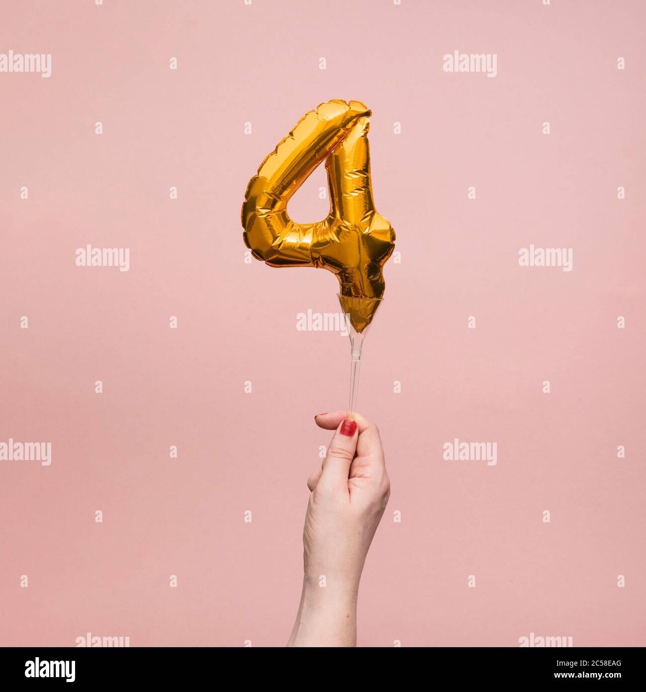 Mano femminile che tiene un numero 4 compleanno anniversario celebrazione palloncino oro Foto Stock