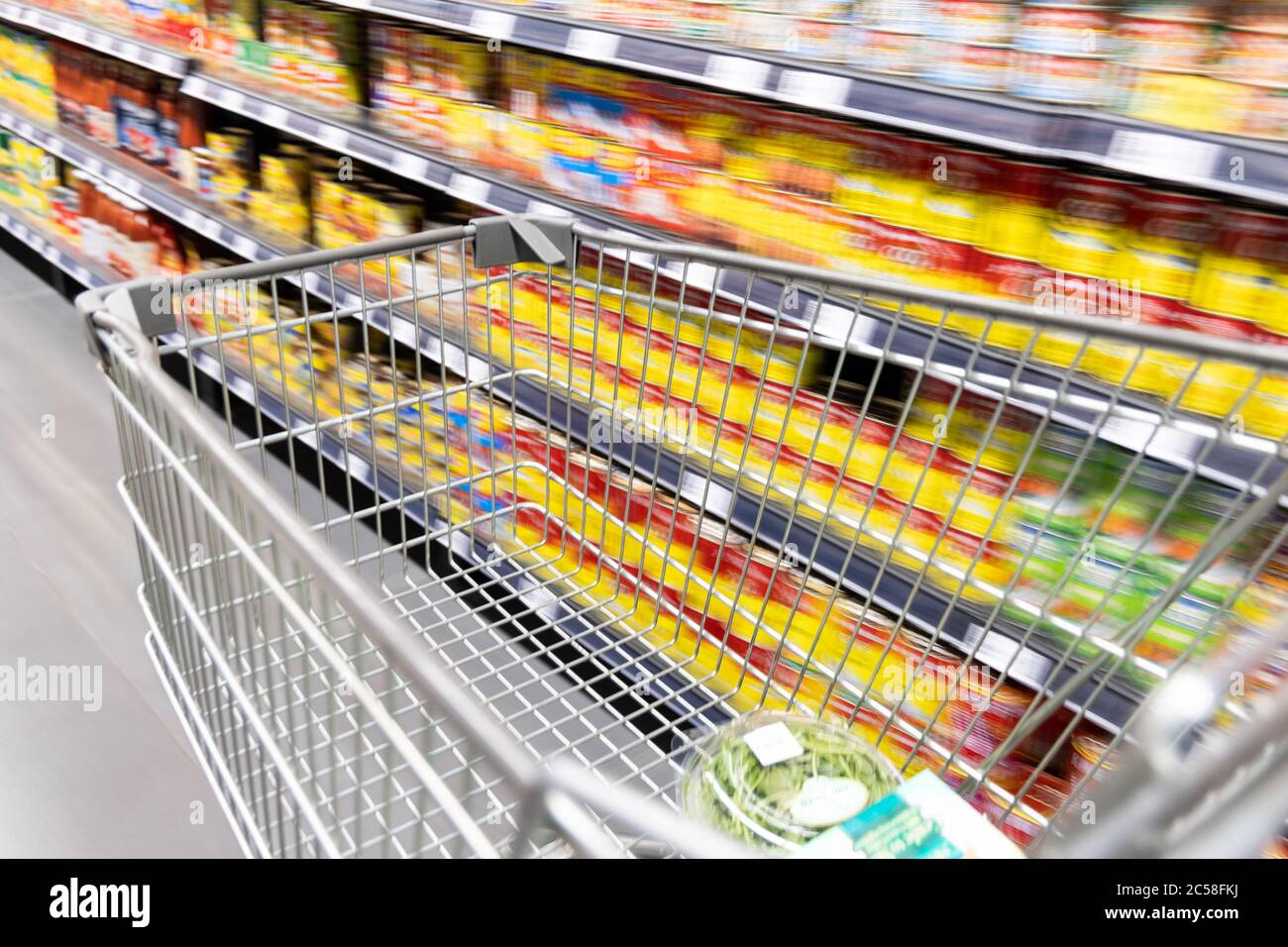 Carrello carrello di shopping che si muove in supermercato con movimento blur corsia con sfondo drogheria Foto Stock