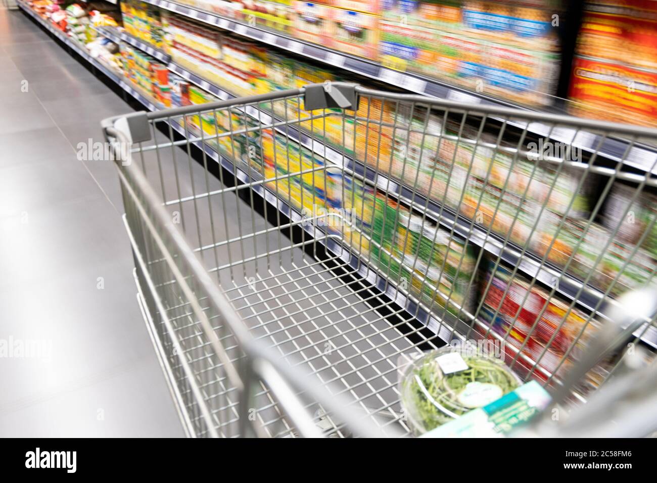 Carrello carrello di shopping che si muove in supermercato con movimento blur corsia con sfondo drogheria Foto Stock