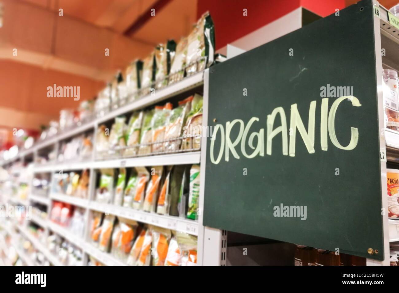 Segnaletica biologica presso la navata del supermercato con merce defocata sullo scaffale Foto Stock