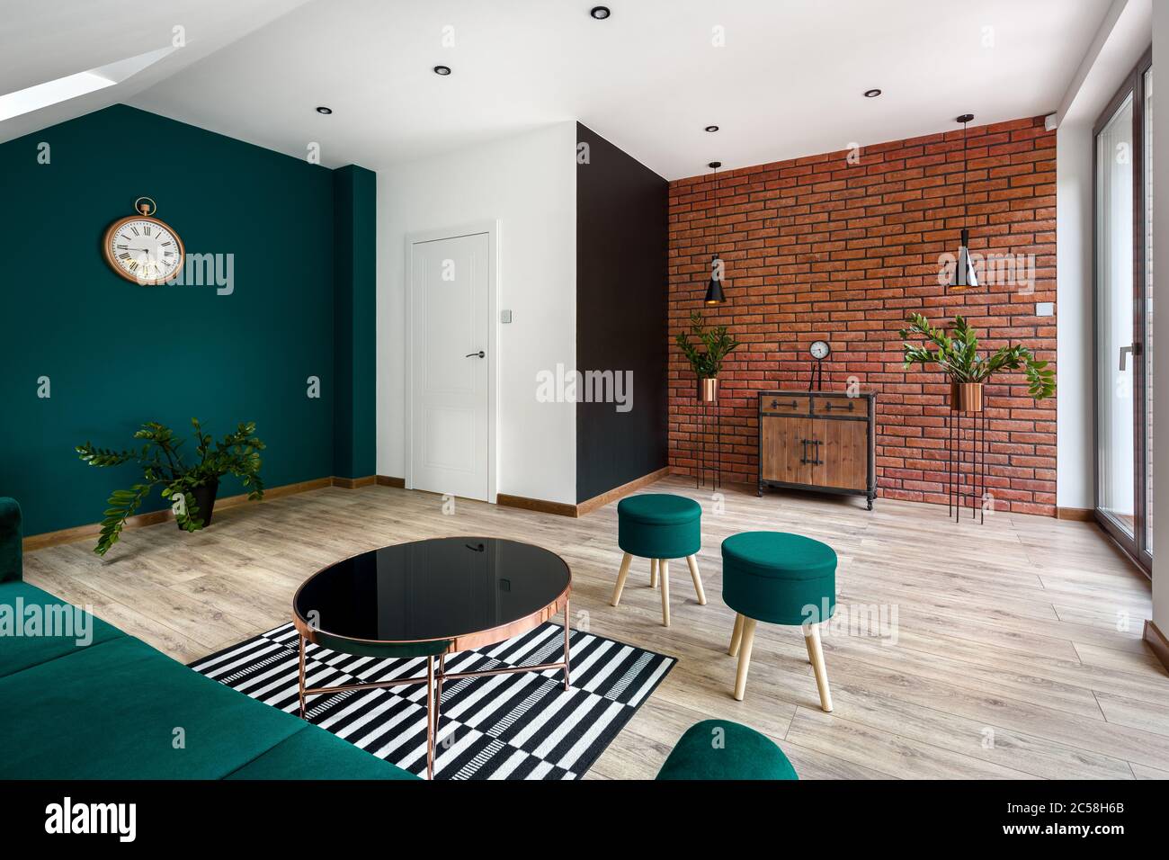 Soggiorno dal design moderno con pareti in mattoni e splendidi arredi e pareti color verde smeraldo Foto Stock