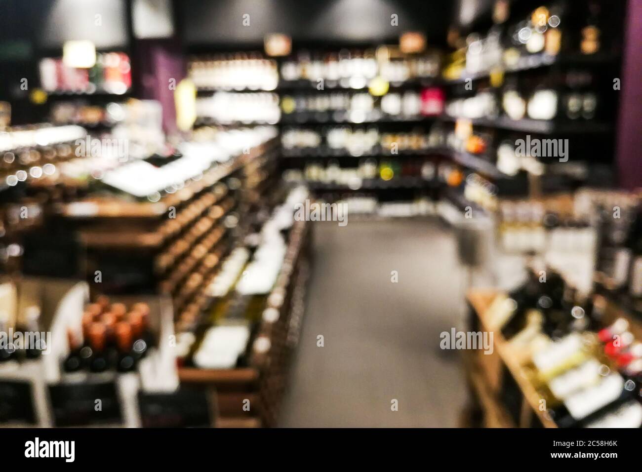 Sezione vino sfocato del rivenditore con bottiglie su scaffale display rack. Utilizzare come sfondo nella ricerca grafica Foto Stock