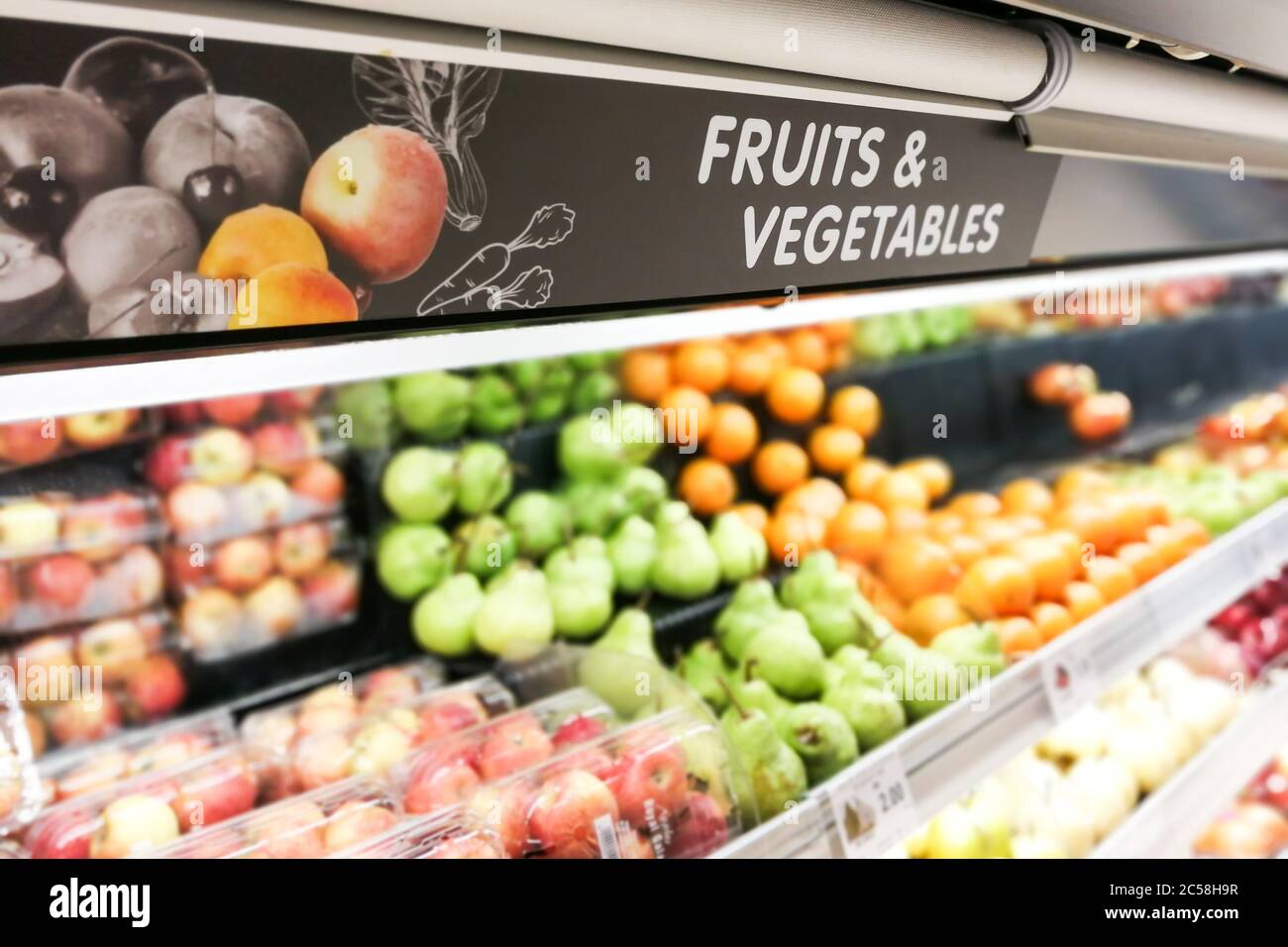 La segnaletica per frutta e verdura al supermercato ha prodotto una sezione di cibo con sfondo sfocato Foto Stock