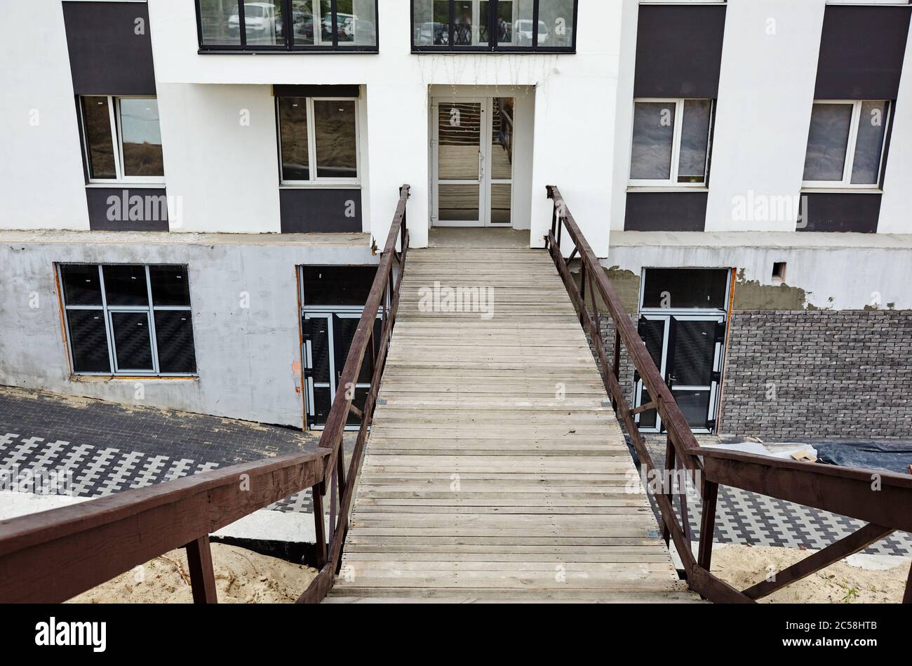 Ponte di legno per cantiere. Costruzione in cemento. Facciata di un moderno edificio di appartamenti europeo Foto Stock
