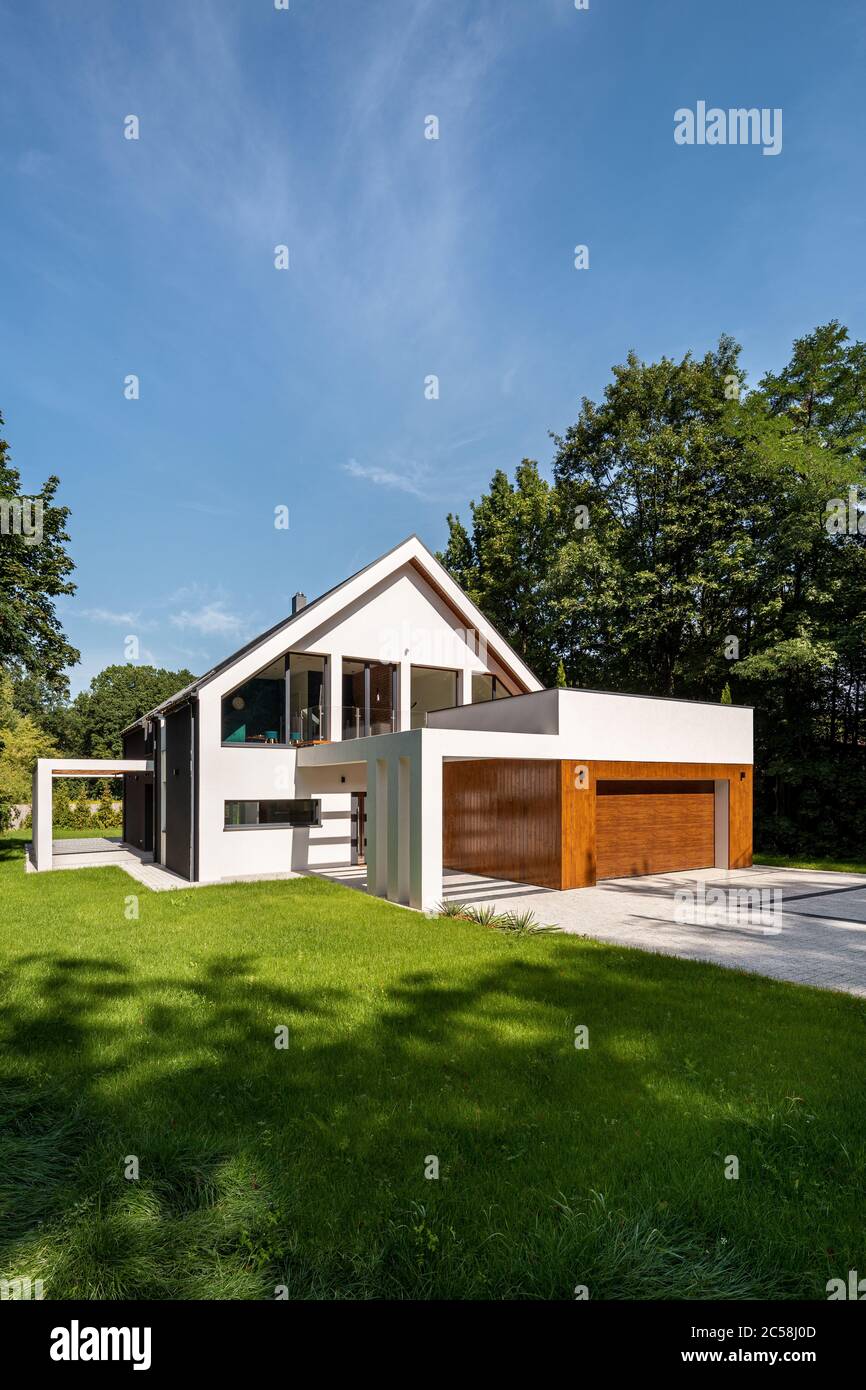 Esterno della casa dal design moderno con grande giardino verde e alberi Foto Stock