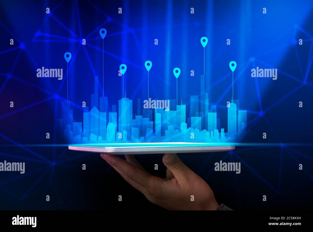 Tavoletta con tenuta a mano con edifici holografici su sfondo blu Foto Stock