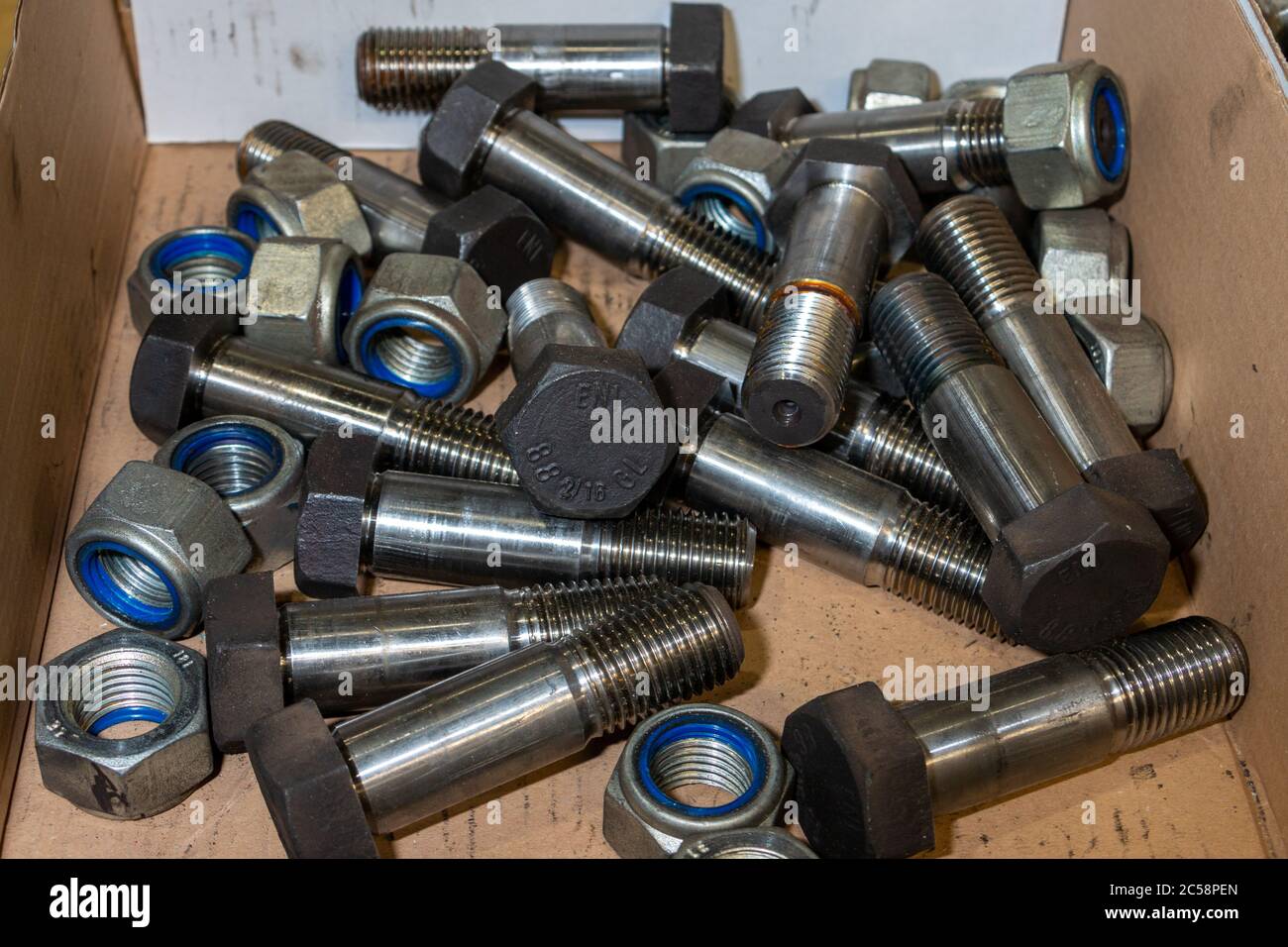 Bulloni grandi e dadi autobloccanti in una scatola di cartone per uso industriale Foto Stock