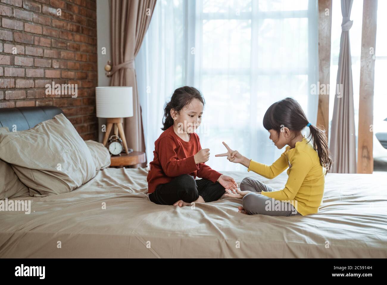 avendo divertimento due ragazze che giocano le forbici della carta di  roccia mentre sedendosi sul letto nella camera da letto Foto stock - Alamy