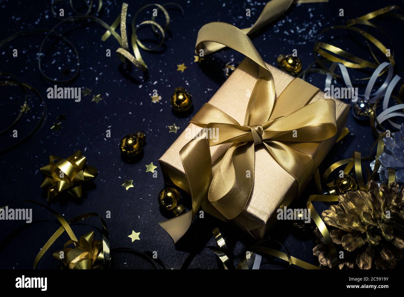 Buon natale, Natale e celebrazione concetti con scatola regalo e ornamento in colore dorato su sfondo scuro.stagione invernale e giorno di anniversario Foto Stock