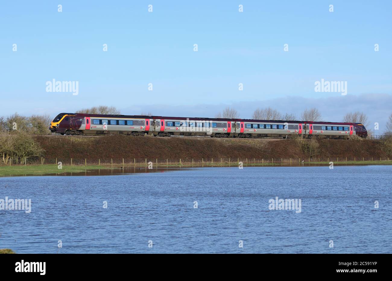 Treno passeggeri Voyager diesel-elettrico di classe 220, che passa per terra allagata a Staffordshire, Inghilterra, Regno Unito. Foto Stock
