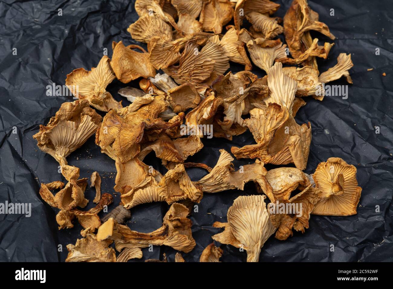 funghi secchi su carta nera sbriciolati. un mazzo di funghi secchi Foto Stock