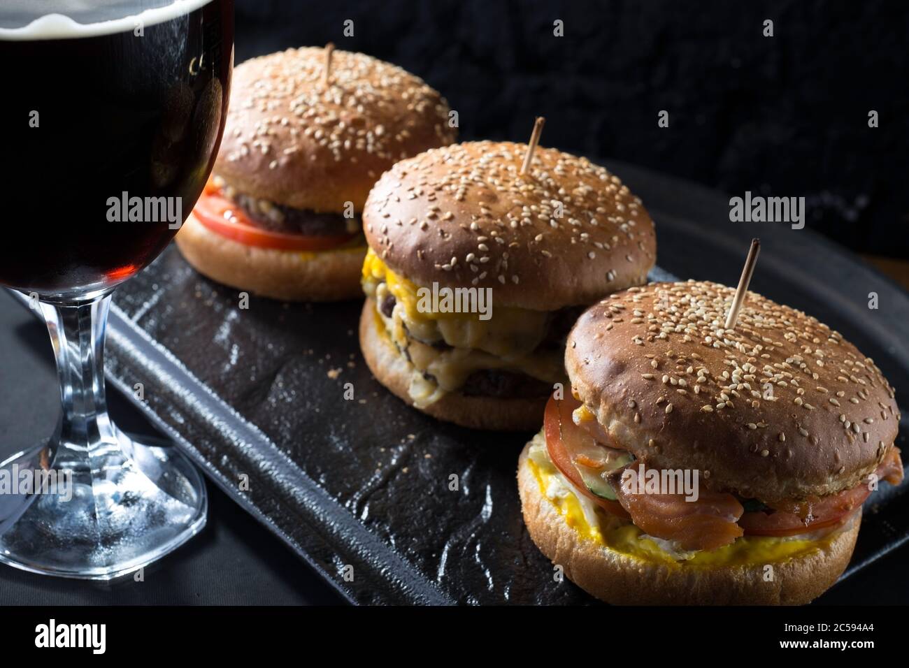primo piano, bicchieri da birra con birra artigianale scura e chiara con schiuma, sullo sfondo di hamburger, con una varietà di ingredienti, tra cui lo shyomga Foto Stock