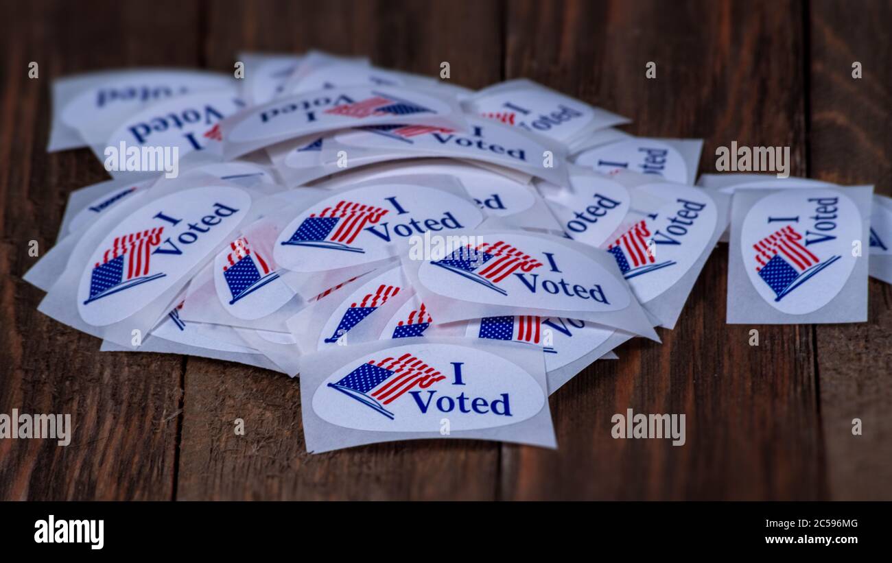 Denver, CO--30 giugno 2020; pila di adesivi votanti rosso bianco e blu siedono su tavola di legno un posto di polling durante le elezioni primarie in Colorado a b Foto Stock