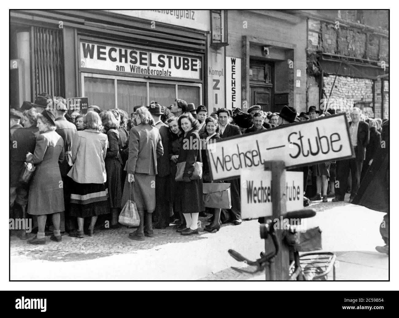 Post-Guerra Ovest Germania 1948 Money Exchange. Folle presso l'ufficio di cambio (Wechsel Stube) il 20 giugno 1948 una riorganizzazione del sistema monetario nelle zone di occupazione della Germania occidentale. È entrata in vigore una riforma valutaria e dal 21 giugno 1948 il Deutsche Mark ha sostituito il Reichsmark e i mezzi di pagamento Rentenmark sono diventati invalidi. Dopo la seconda guerra mondiale, le merci sono rimaste molto scarse. Cibo e altri prodotti erano disponibili solo in piccole quantità e solo attraverso buoni alimentari e certificati di acquisto. Foto Stock