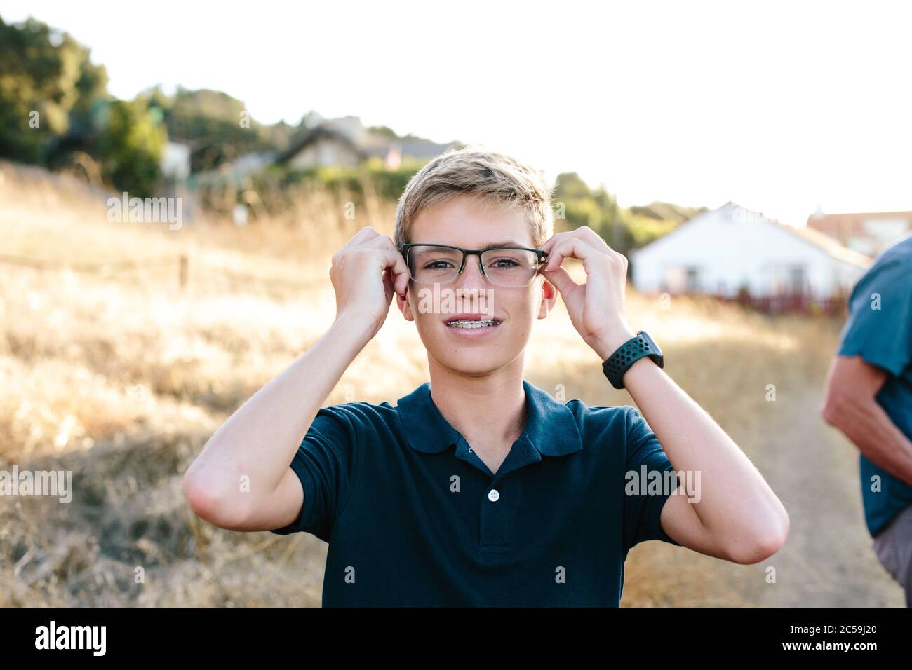 Ritratto di un ragazzo teen con i braces che provano su di lui Occhiali di papà Foto Stock