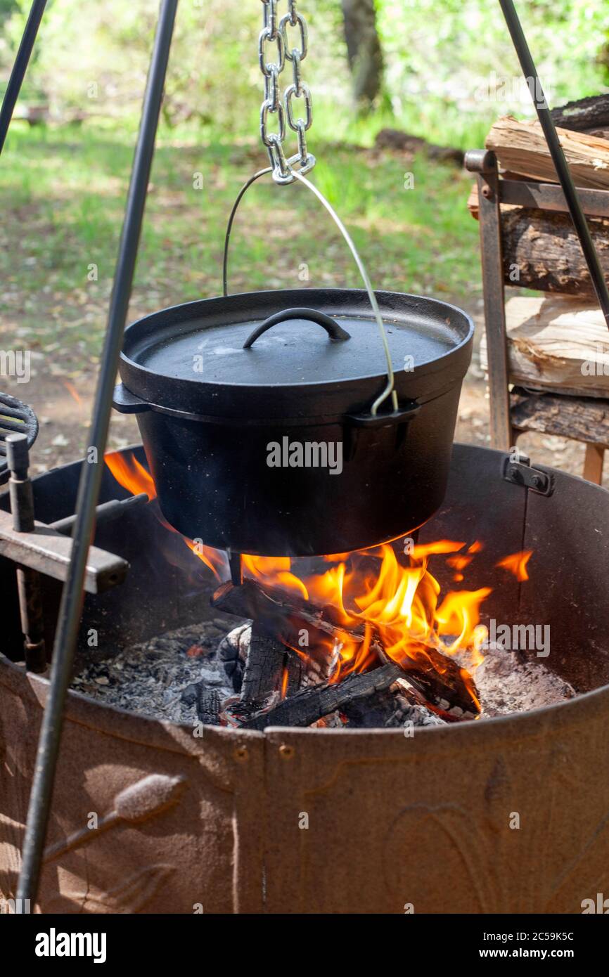 Cucinando fuori griglia con forno olandese su un fuoco aperto Foto Stock