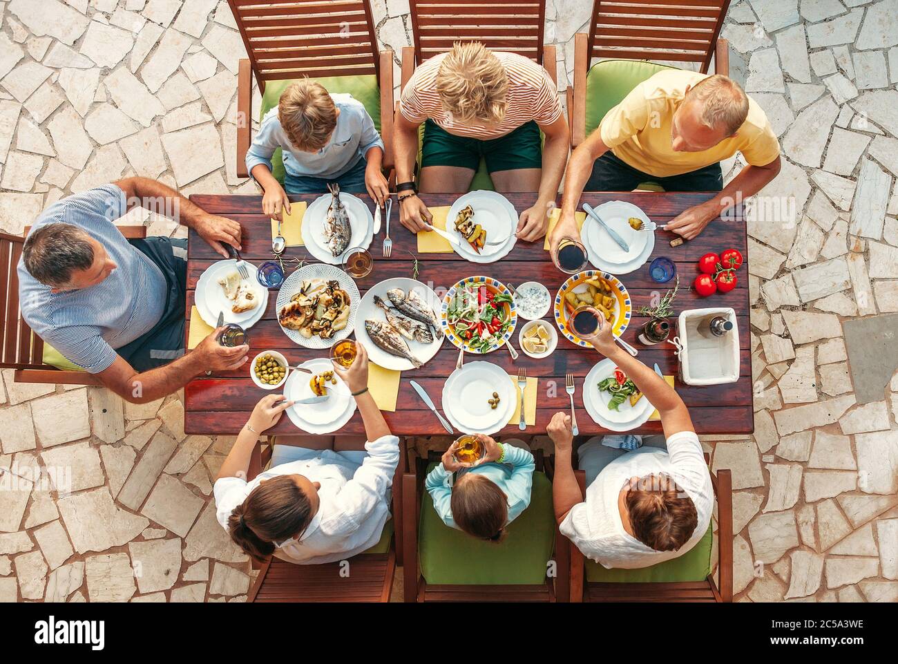 Grande cena multigenerazionale in corso. Tavolo con cibo e mani. Consumo di cibo e famiglia multigenerazionale immagine di concetto di vista dall'alto Foto Stock
