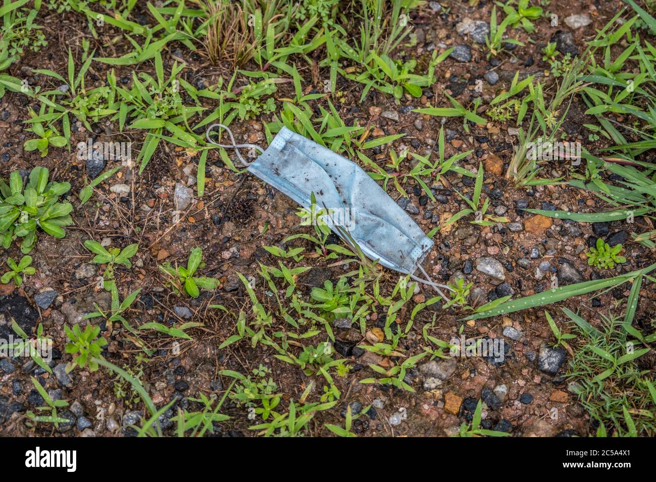 Una maschera di protezione da terra bagnata e sporca, che inquina l'ambiente durante la pandemia del covid-19 Foto Stock